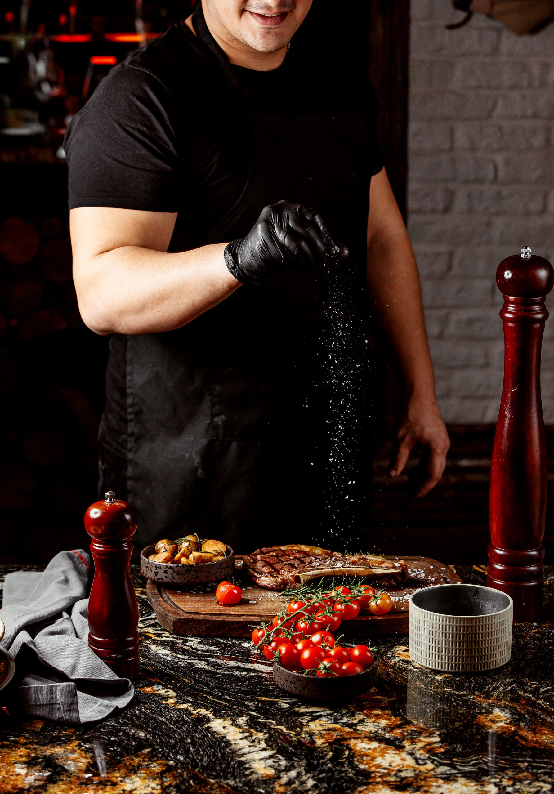 Chalet chef seasoning a steak during high-end food preparation
