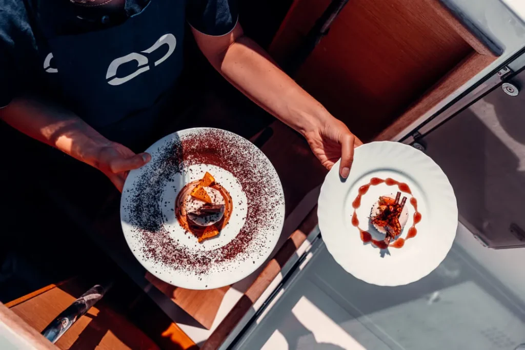 Two dessert plates being served on a yacht by host