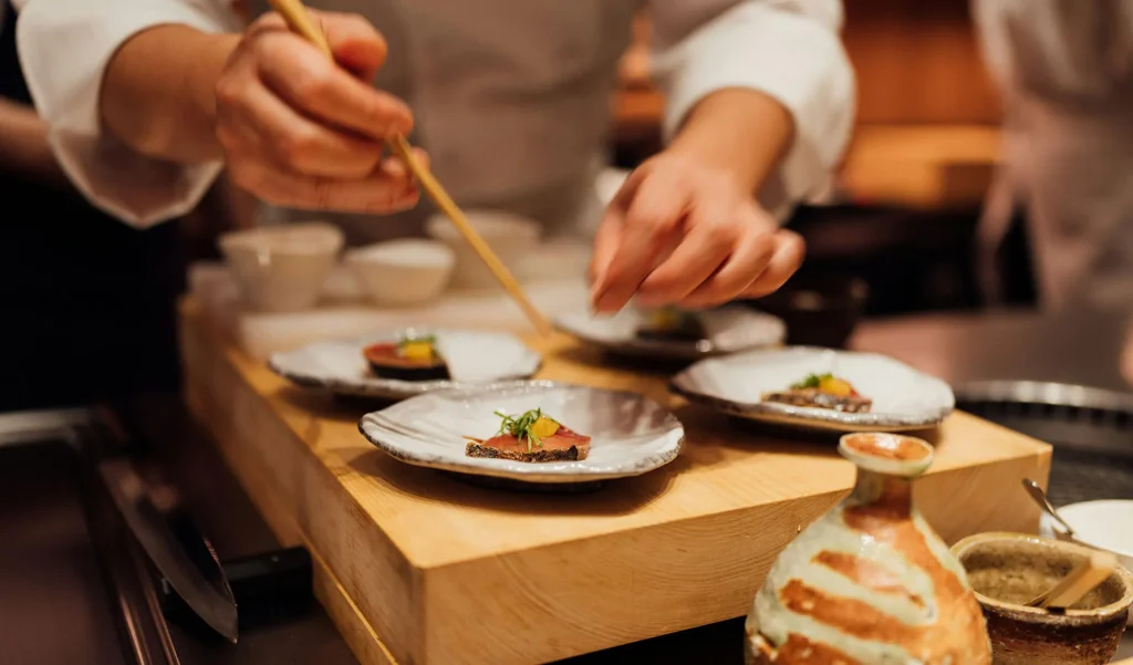Private chef preparing and plating gourmet dishes in a professional kitchen