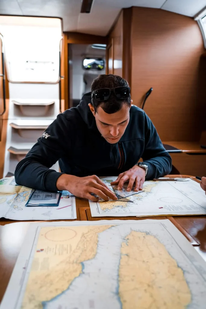 Yacht skipper reviewing navigation charts and passage planning documents