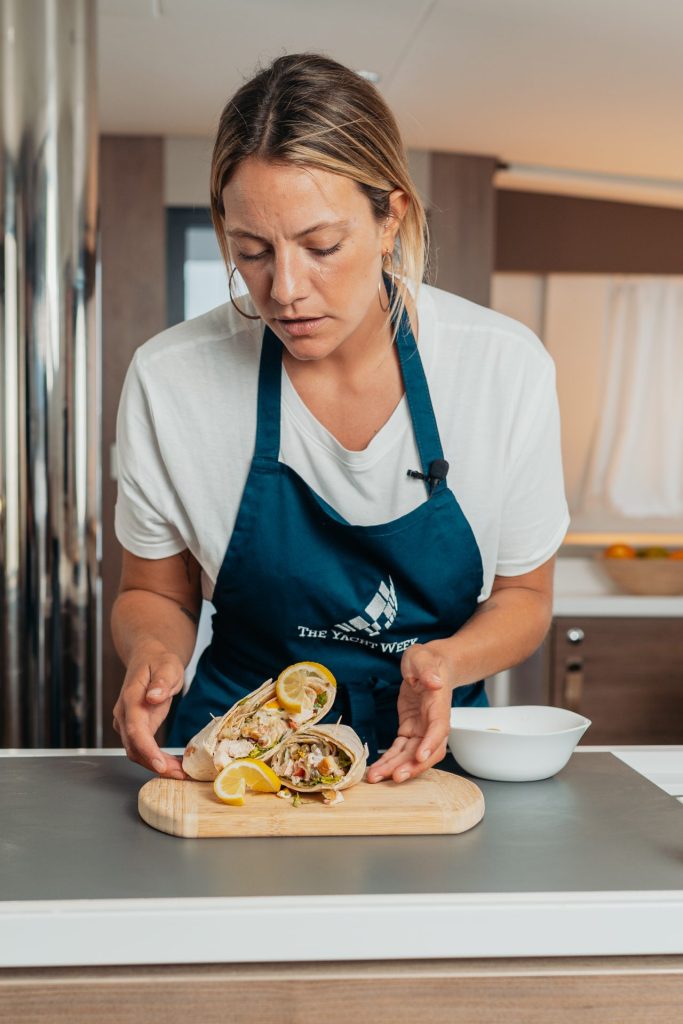 Yacht chef plating a prepared seafood dish in the galley