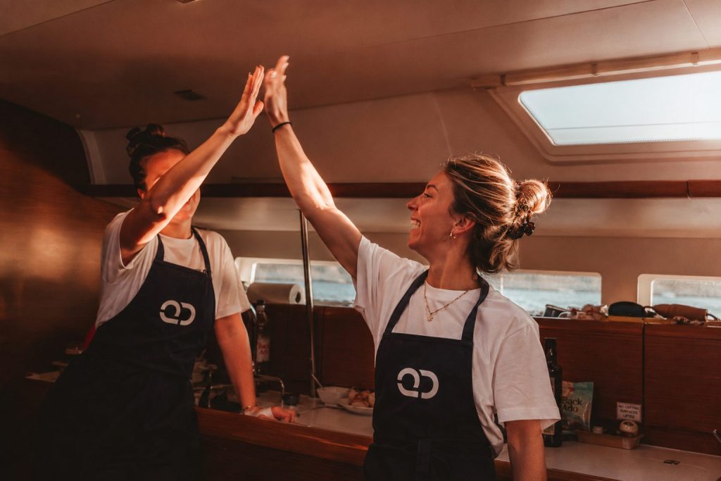 Galley Academy and two students high-fiving on a yacht