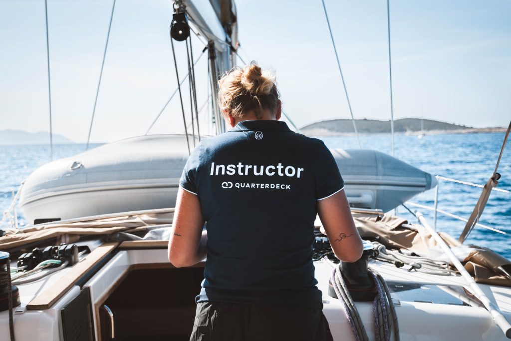 Female Quarterdeck instructor standing on the deck of a sailboat while under way.